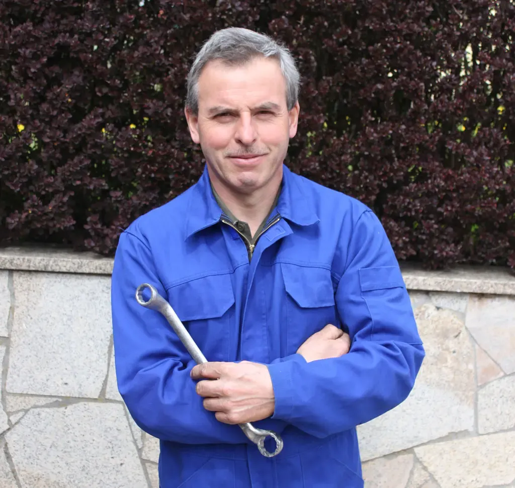 Lothar Zeitler im blauen Arbeitsanzug mit Schraubenschlüssel