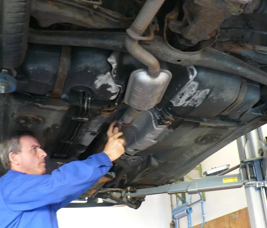 Lothar Zeitler arbeitet an der Abgasanlage unter einem Auto auf der Hebebühne